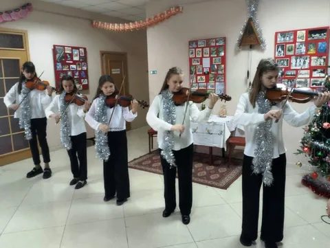 Ансамбль скрипачей с серебристой мишурой на плечах