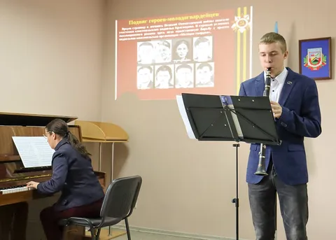 Кларнетист и концертмейстер, на экране — портреты молодогвардейцев